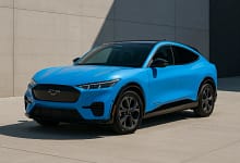 2025 Ford Mustang Mach-E in Grabber Blue parked beside a minimalist wall.