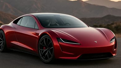Red 2026 Tesla Roadster on mountain road at sunset.